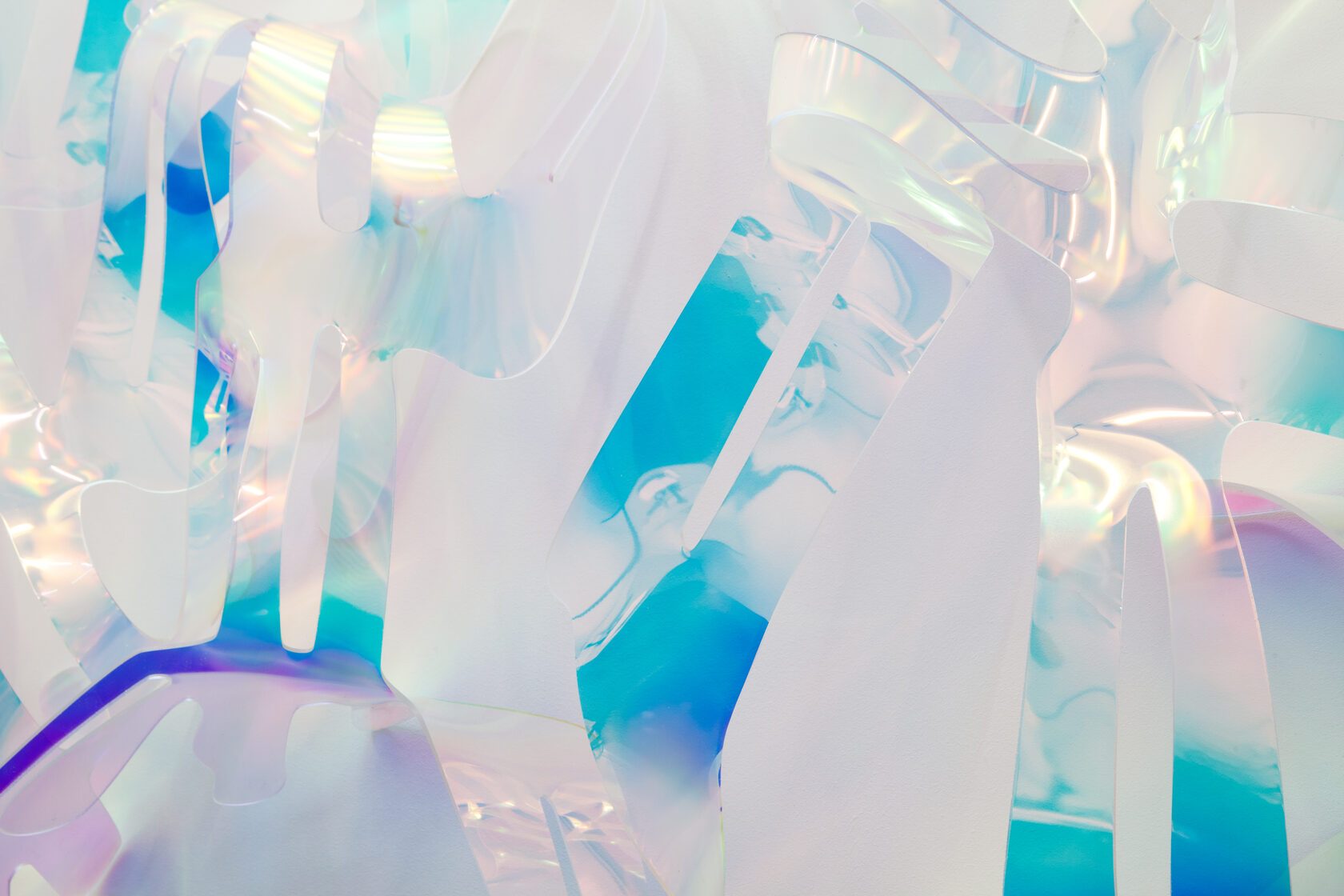 A detail of a sculpture: overlapping translucent strips of acrylic glass in iridescent cyan, blue and violet with opaque white, filling the frame.